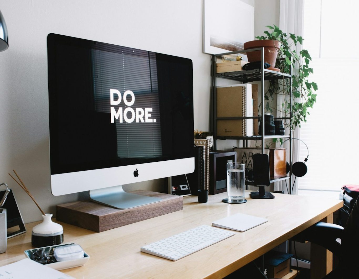 Escritorio moderno con un ordenador, una planta y un mensaje que dice "DO MORE".