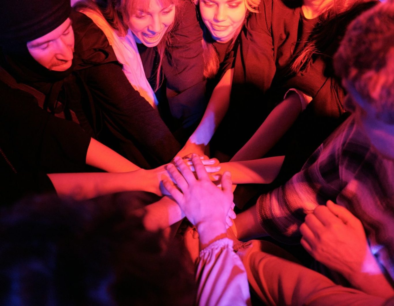 Grupo de personas uniendo sus manos en un ambiente festivo y colorido.