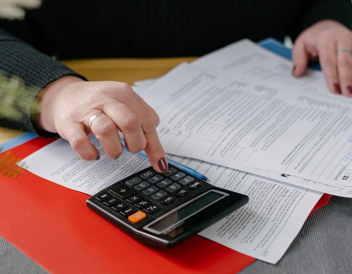 Mano usando una calculadora sobre papeles de documentos y informes.