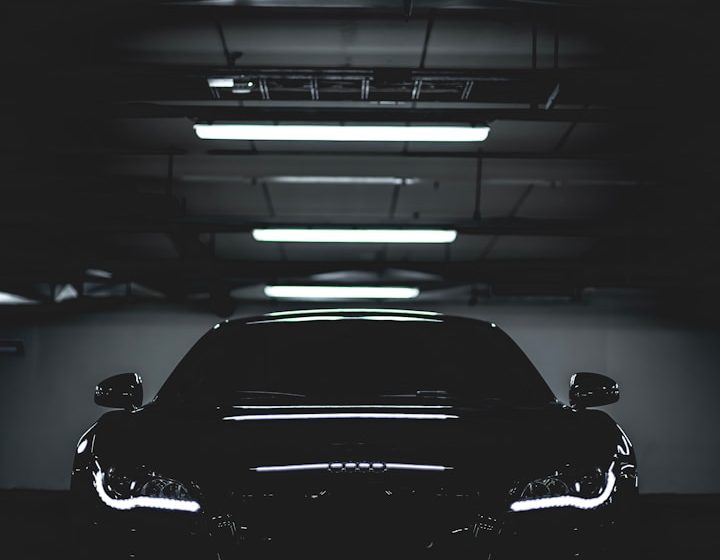 Coche negro elegante en un aparcamiento oscuro, con luces brillantes en el techo.
