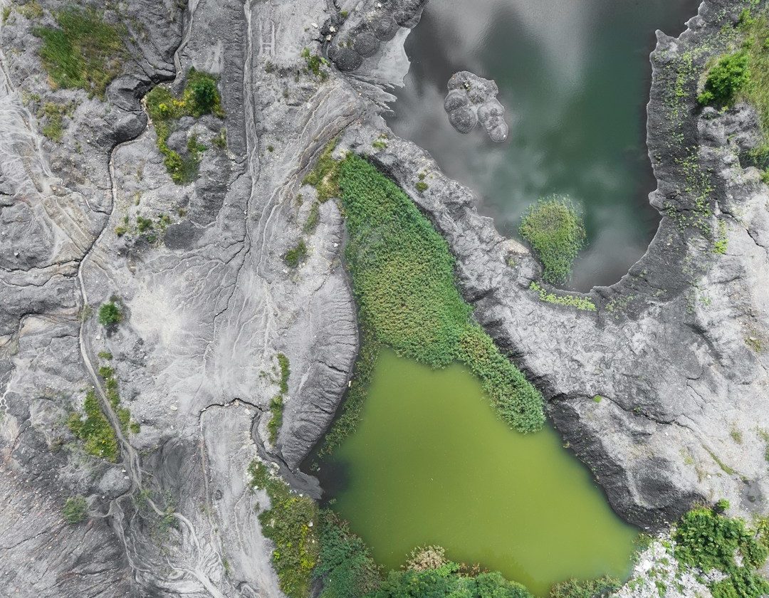 Vista aérea de un paisaje rocoso con un lago verde rodeado de vegetación.
