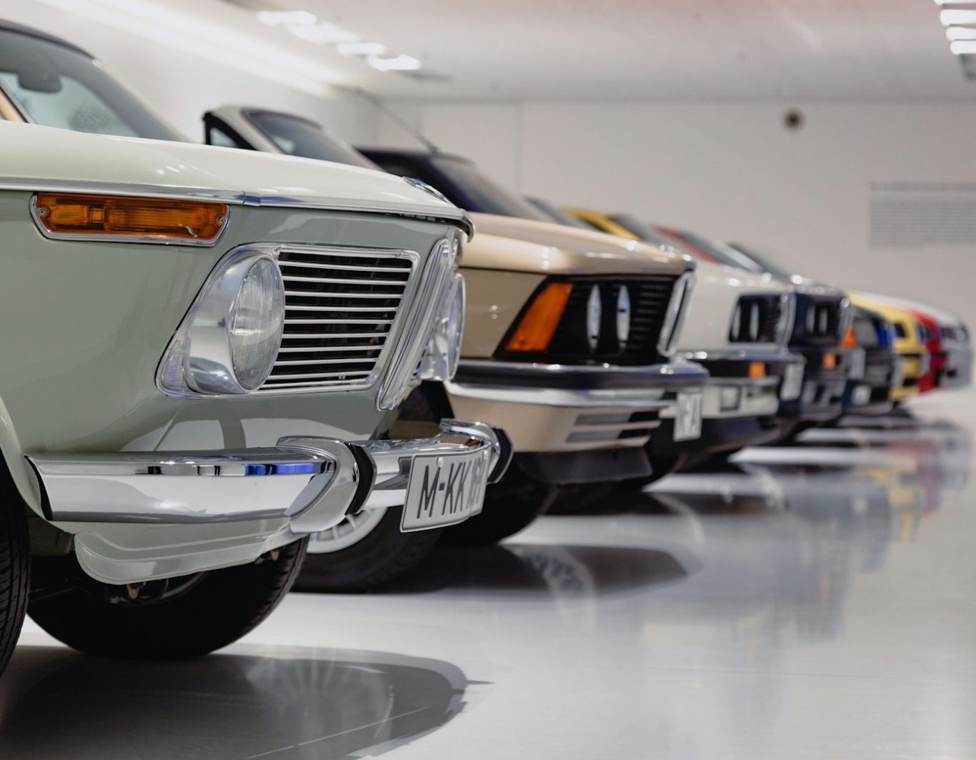 Filas de coches clásicos alineados en un garaje con suelo brillante.