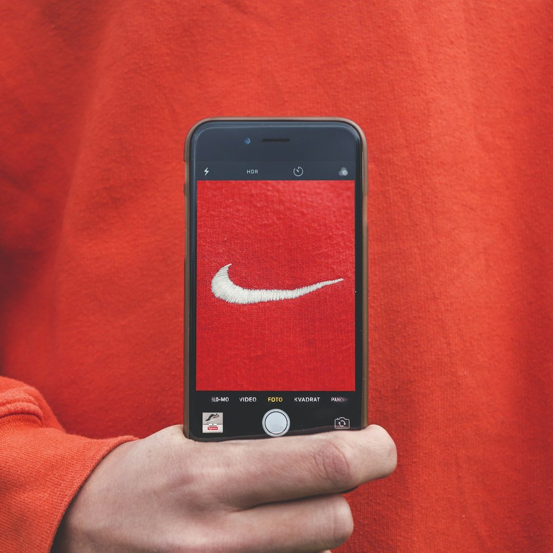 Un teléfono móvil muestra el logotipo de Nike sobre un fondo rojo.
