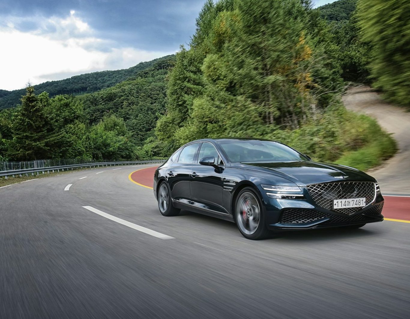 Coche negro deportivo circulando por una carretera sinuosa en un paisaje montañoso.