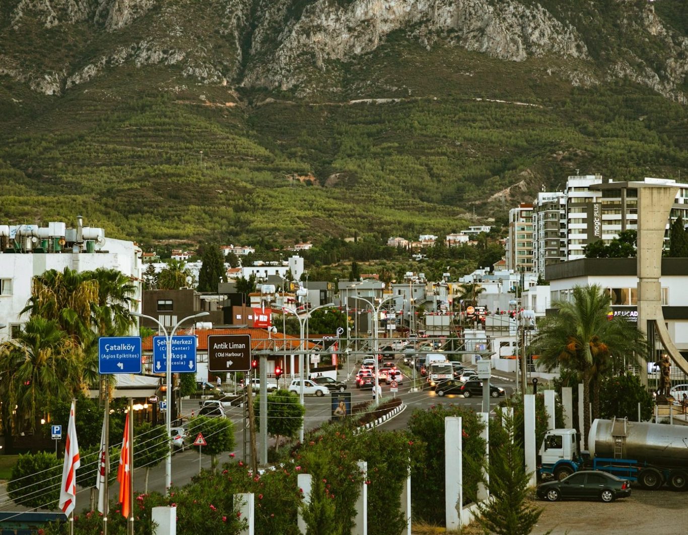 Vista urbana con edificios, tráfico y montañas al fondo.